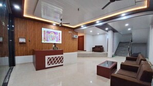 A modern lobby with a reception desk, seating area, and a staircase. - RAGHAVAM (Faizabad)