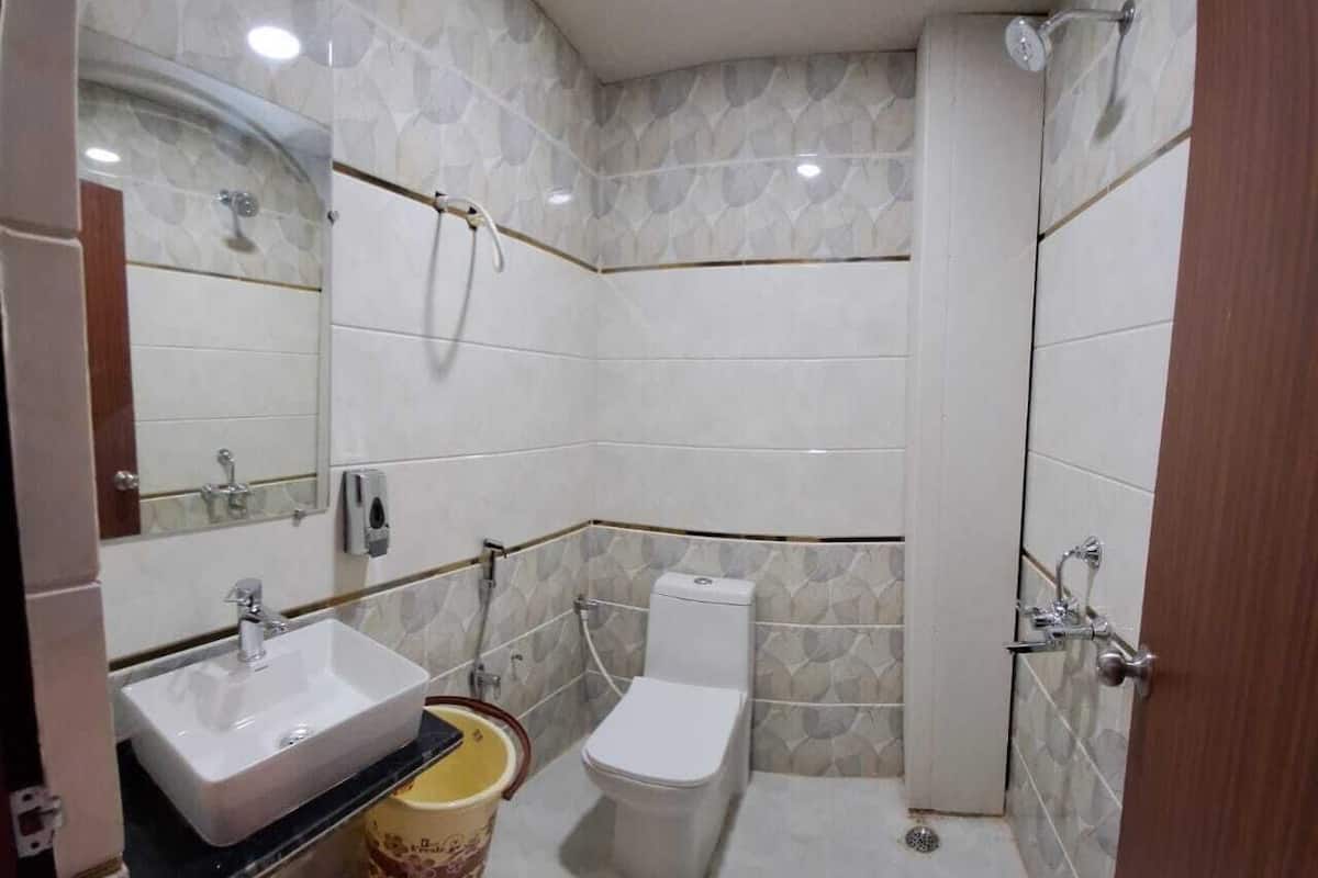 Casa de banho compacta com lavatório, sanita e chuveiro.