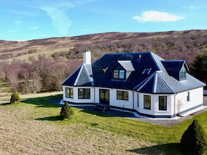 Ein großzügiges, modernes Haus mit einem steilen Satteldach, vielen Fenstern und einem gepflegten Rasen.