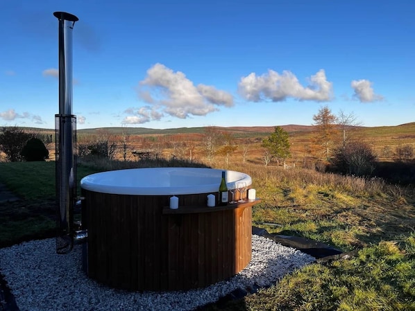 Ein Whirlpool in einer Außenanlage, mit blauem Himmel und sanften Hügeln in der Ferne.