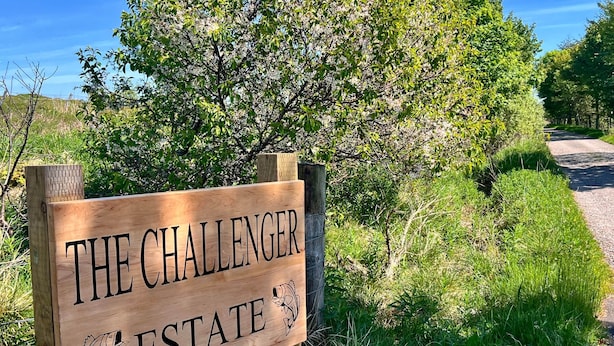 Un letrero de madera con el texto 'THE CHALLENGER ESTATE' e ilustraciones de peces.