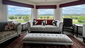 Una habitación amplia con un gran ventanal, un sofá, una silla y una mesa.