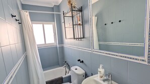 A bathroom with a bathtub, toilet, sink, and a large mirror. - 202 - Livingtarifa Dolce Vita (Tarifa)