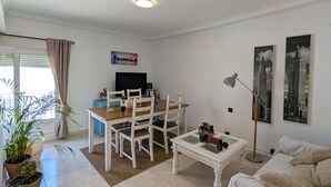 A living room with a dining table, chairs, a sofa, a coffee table, a lamp, and a TV. - 202 - Livingtarifa Dolce Vita (Tarifa)