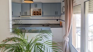 A modern kitchen with light blue cabinets, a central island, and a hanging pendant light. - 202 - Livingtarifa Dolce Vita (Tarifa)