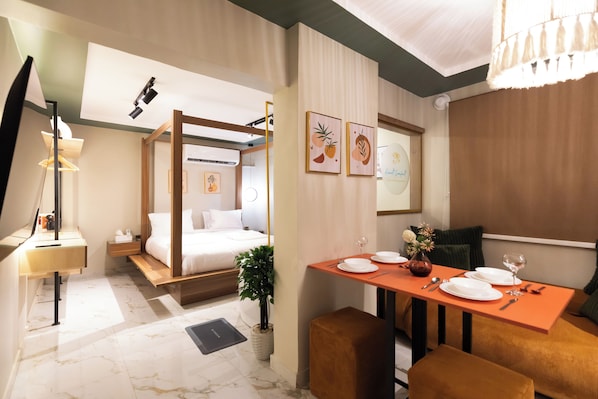 Une chambre d’hôtel comprenant un lit, une table de chevet, une lampe et un coin repas avec une table dressée pour deux personnes.