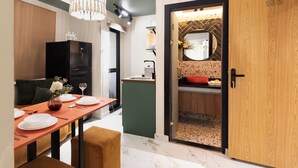 A modern kitchen with a wooden door, a dining area with a table set for two, and a kitchen island. - Delightful Hygiene Jacuzzi Junction Massager 5Min toCAairport studio in Cairo (Cairo Governorate)