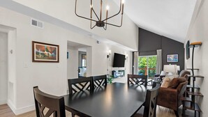 A modern living space with a dining area, a sofa, and a TV mounted on the wall.