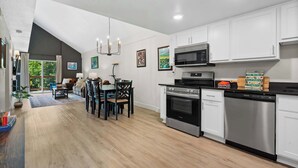 A modern kitchen with white cabinets, stainless steel appliances, and a dining area with a table and chairs.