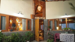A cozy interior with a wooden door labeled "Sid's Nest," stone walls, and potted plants. - The Whispering Pines (Dhari)