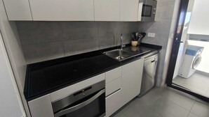 A modern kitchen with stainless steel appliances, a black countertop, and a dishwasher. - Beautiful apartment in Teatinos Málaga (Málaga)