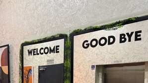 A lobby with a 'WELCOME' sign and a 'GOOD BYE' sign above an elevator.