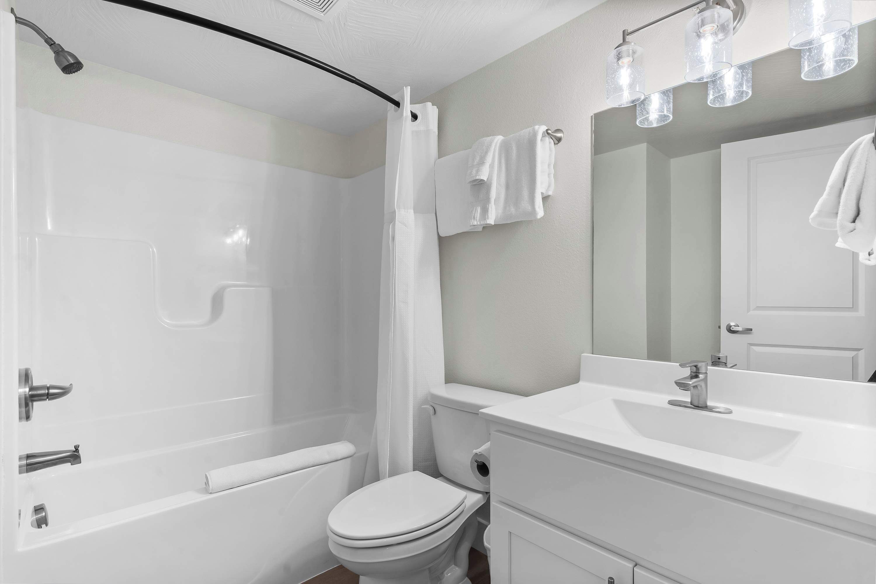A modern bathroom with a shower, toilet, and sink.