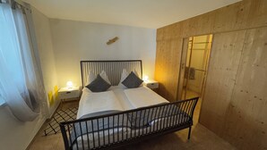 A bed with a metal frame, two bedside tables with lamps, a wooden headboard, and a mirror on the wall. - Vacation apartment Annemarie (Tirol)