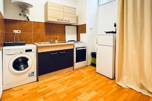 Cocina compacta con lavadora, estufa y refrigerador.