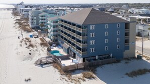 Een hotel aan het strand met meerdere balkons, een zwembad en toegang tot het strand.