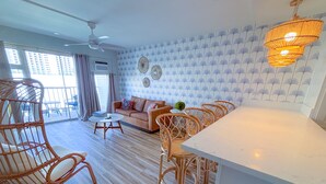 Amplia sala de estar con sofá, sillas de mimbre, una mesa de comedor y un ventilador de techo.