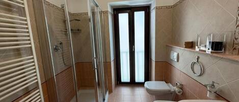 Un baño con ducha envuelta en vidrio, inodoro y lavamanos.
