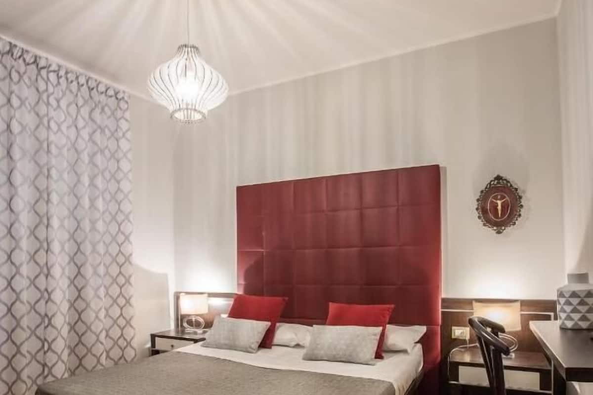 A hotel room with a large bed, a desk, and a chair.
