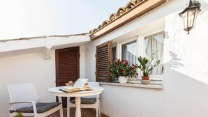 A small patio with a round table and two chairs, a window with shutters, and potted plants. - Hotel Lieto Soggiorno (Assisi)