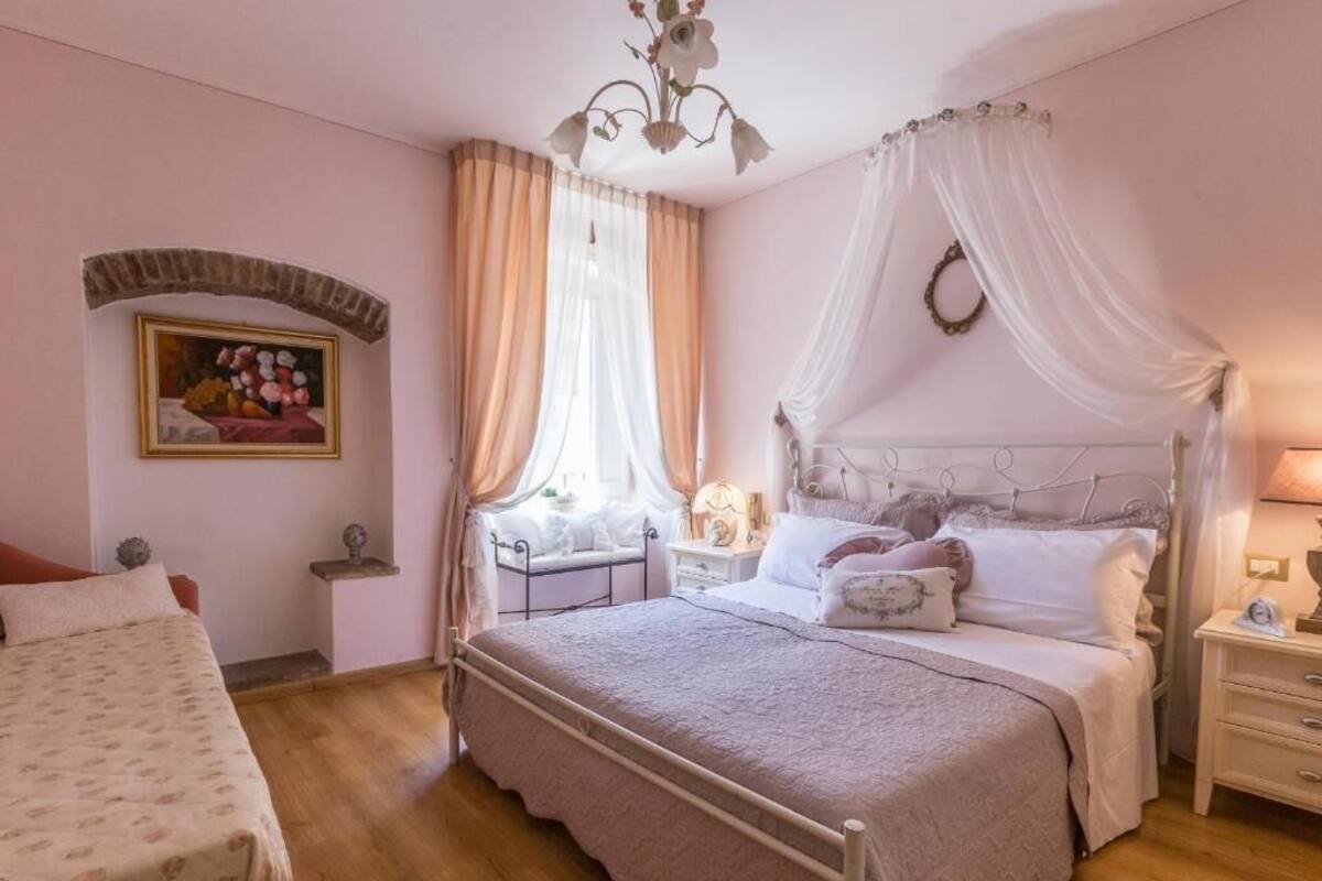 A bedroom with a bed, bedside tables, a nightstand, a chandelier, and a painting on the wall.