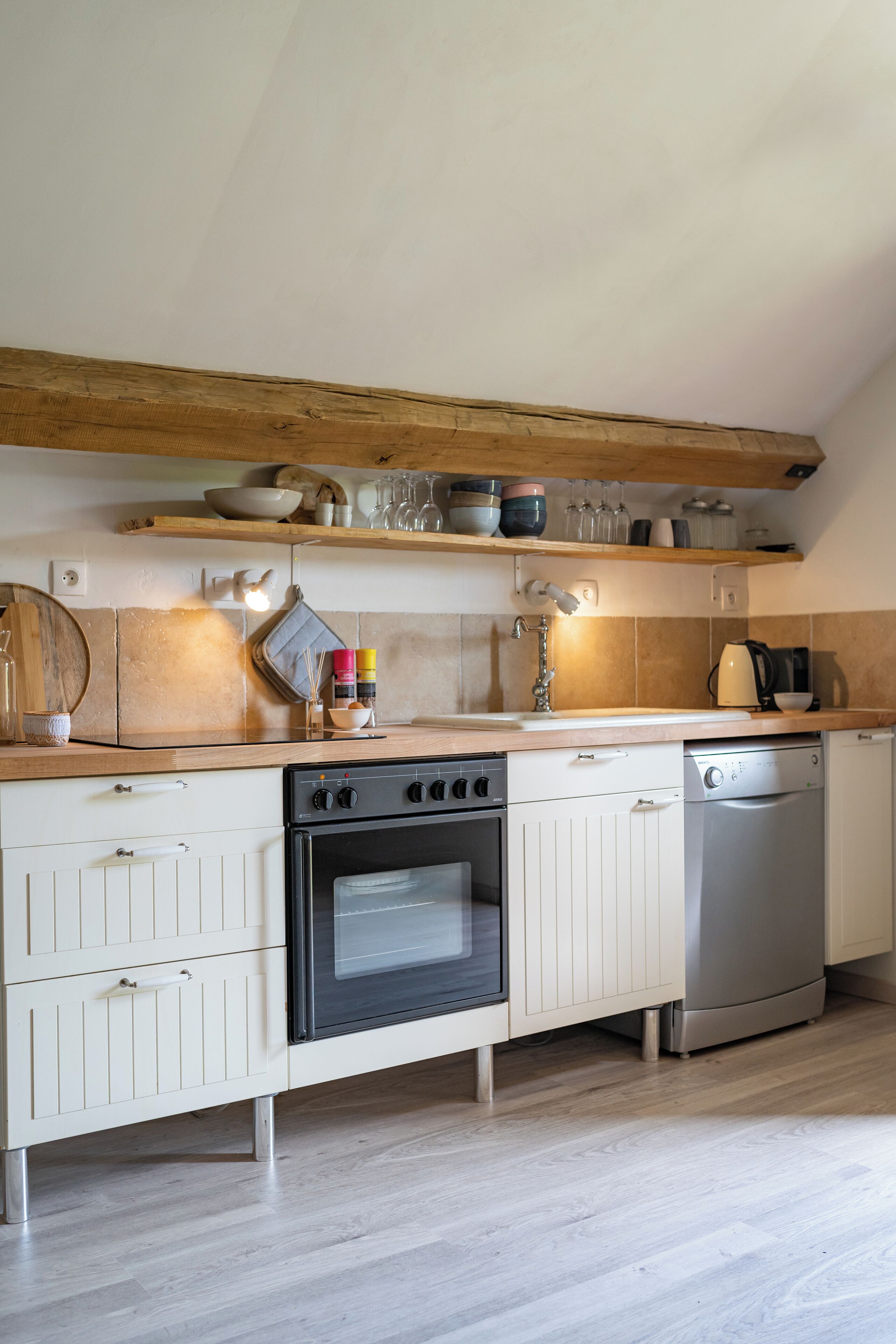 Una cucina con mobili in legno, un fornello, una lavastoviglie e un piano di lavoro con diversi oggetti da cucina.