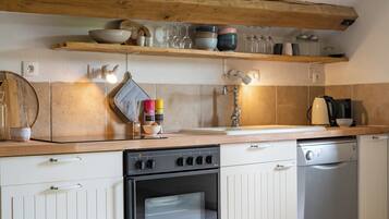 Una cucina con mobili in legno, un fornello, una lavastoviglie e un piano di lavoro con diversi oggetti da cucina.