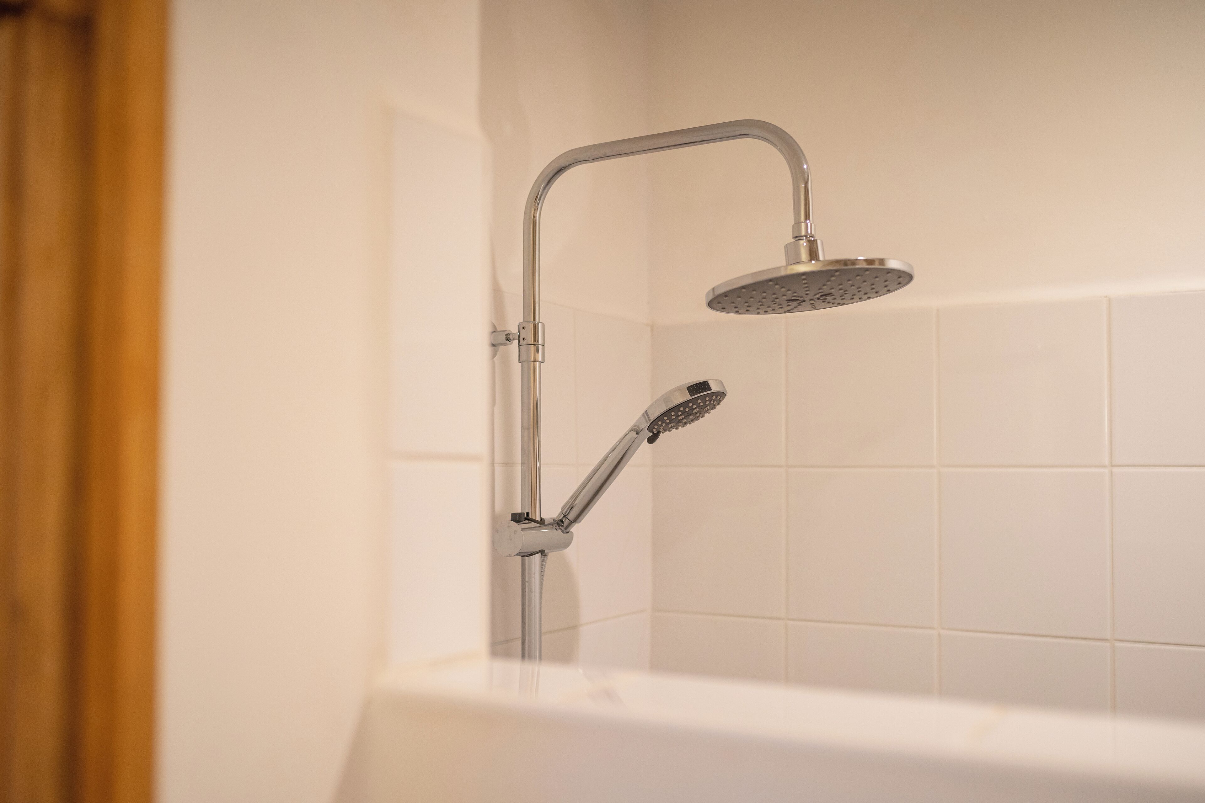 Ein modernes Badezimmer mit Dusche, Badewanne und weißen Fliesen.