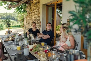 A dining table set outdoors with a stone wall backdrop, various food items, and drinks. - La vallée des Elements (Chiddes)