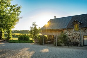A stone house with a gravel driveway, a wooden bench, and a garden area. - La vallée des Elements (Chiddes)