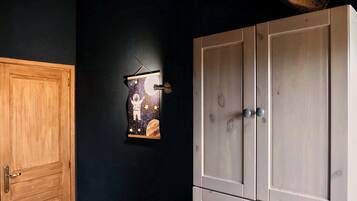 Ein Zimmer mit Holztür, einer dunklen Wand und einem großen Kleiderschrank mit zwei Türen.