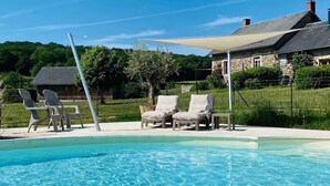 A clear swimming pool with lounge chairs and a stone building in the background. - La vallée des Elements (Chiddes)