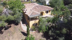 Une maison à deux étages, avec un toit en tuiles, un balcon et un jardin.