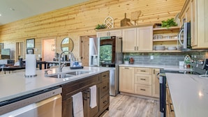 A modern kitchen with wooden cabinetry, stainless steel appliances, and a large island with a dishwasher. - Waterfront Cabin on White River w/ Deck + Patio! (Mountain Home)