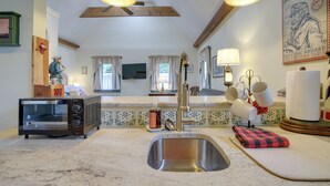 Una cocina con horno tostador integrado, un lavamanos de acero inoxidable y techo de madera.