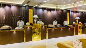 Zona de recepción de un hotel con suelo de mármol, mostrador de recepción con detalles dorados y área de estar con sillones tapizados en amarillo.