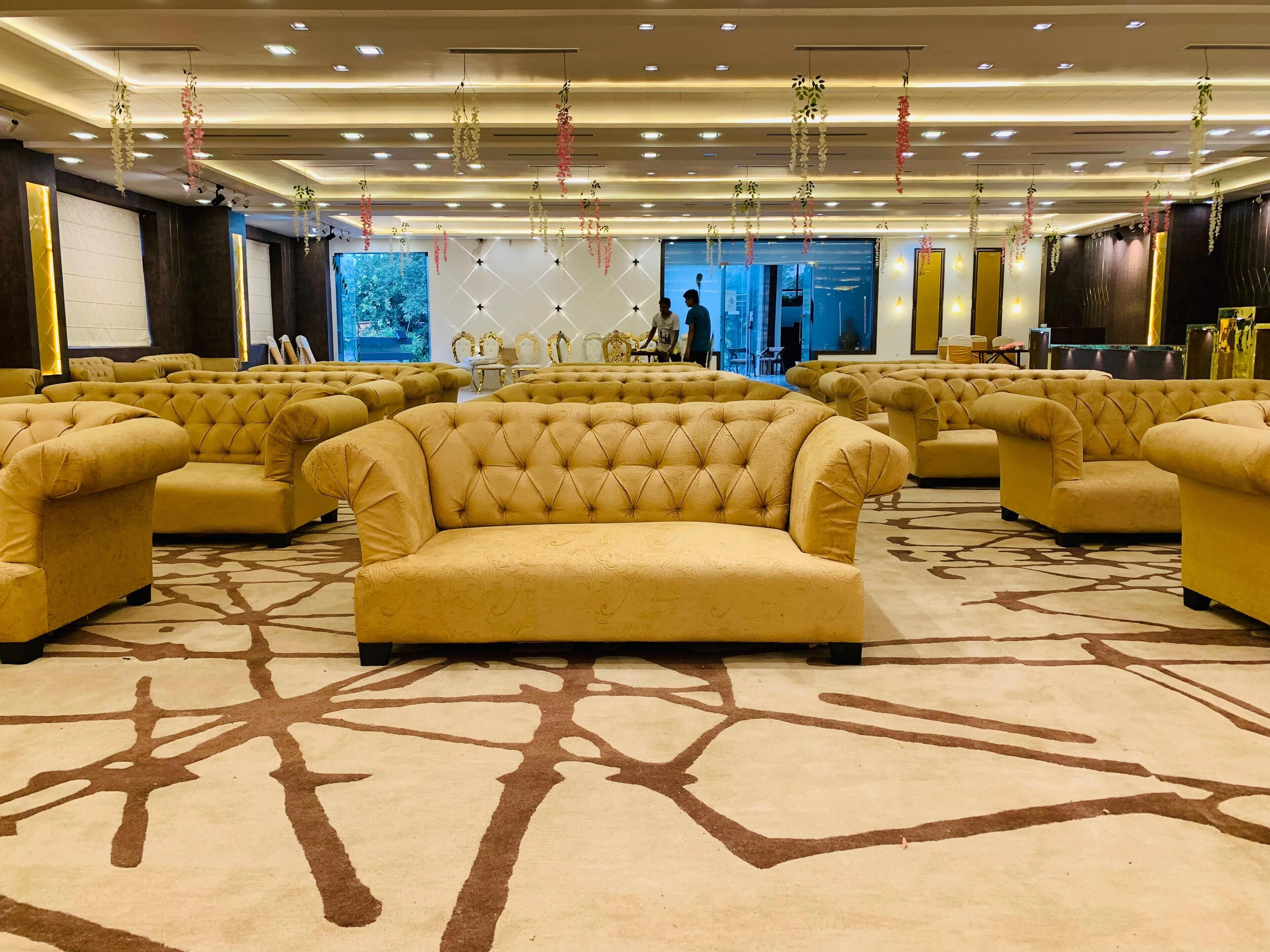 Un amplio vestíbulo de hotel con varias zonas de estar, alfombra estampada y decoraciones florales colgantes.