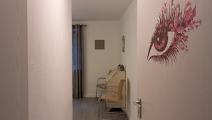 Um quarto com cadeira de massagem, porta com puxador e parede com desenho decorativo de olho.