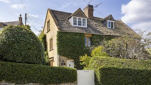 A traditional stone cottage with ivy-covered walls, a stone wall, and a small wooden gate. - Charming dog friendly cottage - Bank Cottage (Longborough)