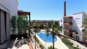 Un edificio moderno con piscina, palmeras y cielo azul despejado.