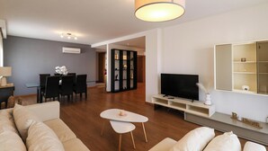 Una sala de estar moderna con un sofá, una mesa de centro, un televisor y un comedor con sillas y una mesa.