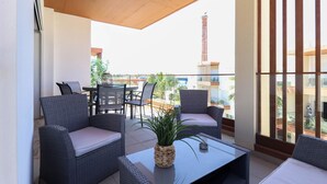 Un balcón con muebles de mimbre, una mesa y una planta en maceta.