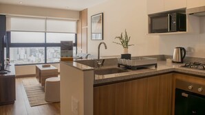 A modern kitchen with a large island, stainless steel appliances, and a city view. - w Elegant 1BR Retreat in the Heart of San Isidro (Lima)