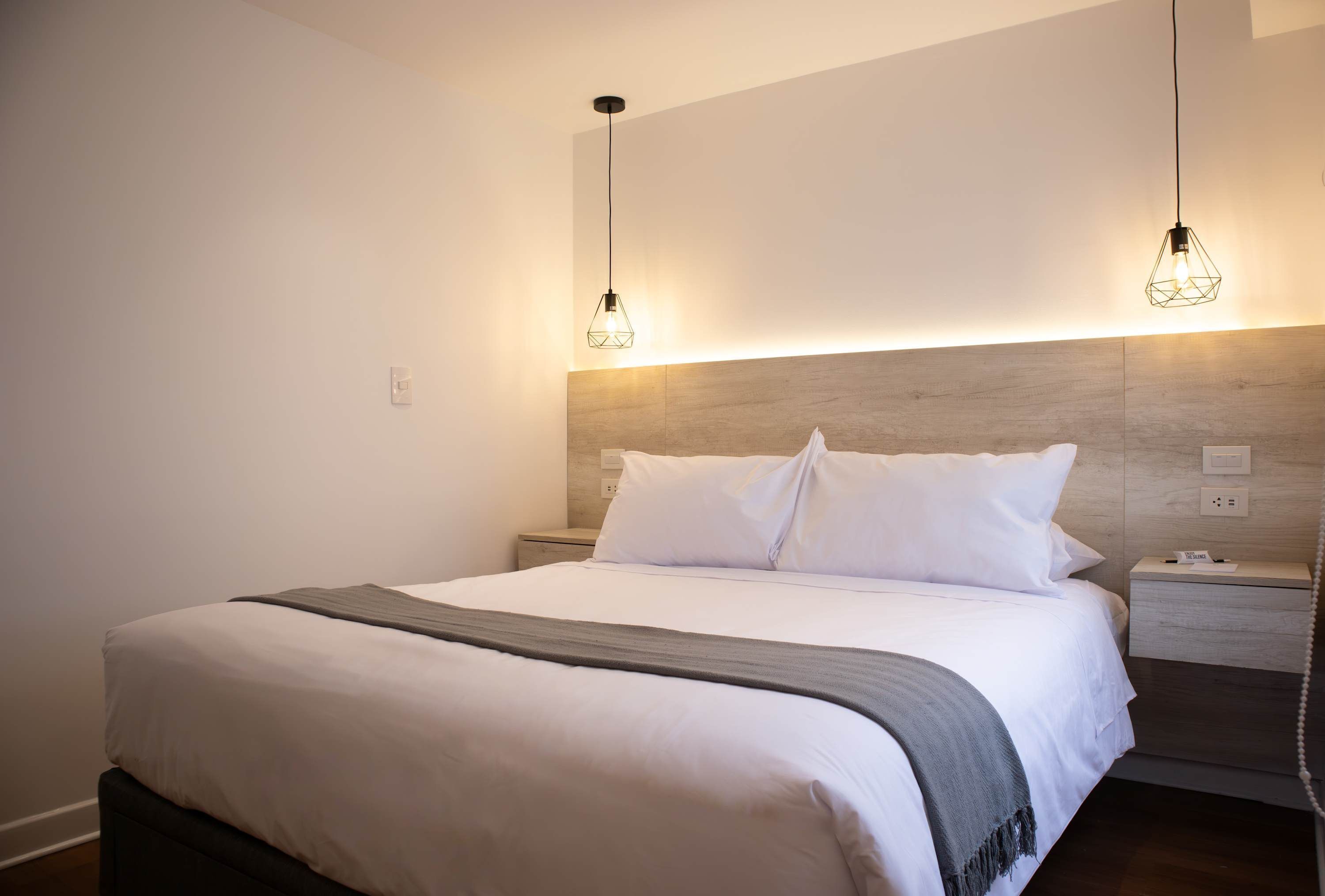 A modern bedroom with a large bed, two bedside tables, and a wooden headboard.