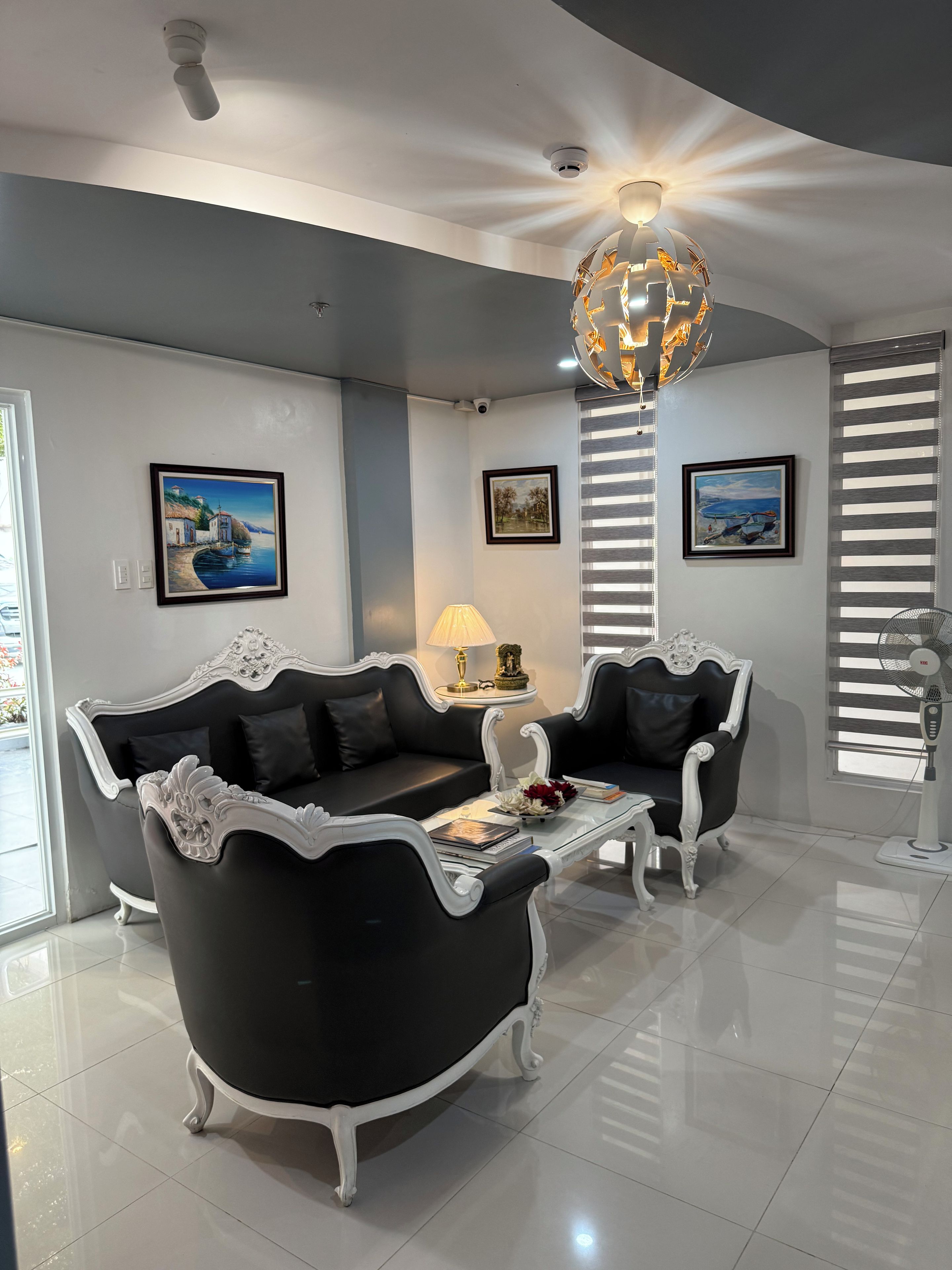 Een moderne woonkamer met een zwart-wit bank, een glazen salontafel en een decoratieve lamp.