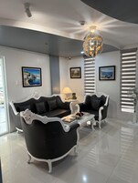 Una sala de estar moderna con un sofá blanco y negro, una mesa de centro de vidrio y una lámpara decorativa.