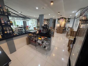 A modern bar area with a counter, shelves of liquor bottles, and a coffee machine. - Leribi Hotel and Restaurant (Tagaytay)