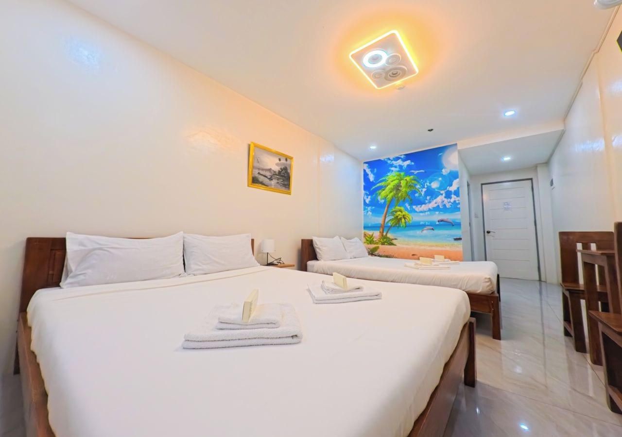 Una habitación de hotel con dos camas, un mural de playa y una puerta que conduce a otra habitación.
