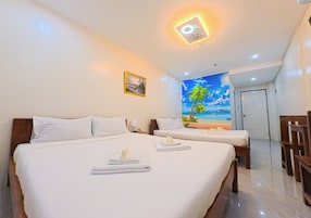 A hotel room with two beds, a beach mural, and a door leading to another room.