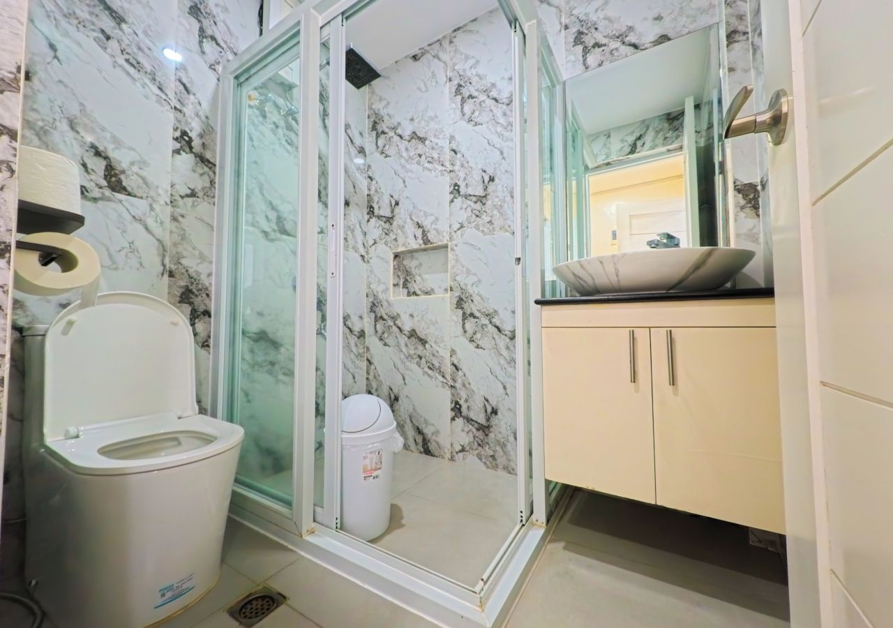 Une salle de bain comprenant des toilettes, une douche à parois de verre, un lavabo et un meuble de rangement.